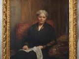 portrait d'une femme en robe noire, assise sur une chaise rouge