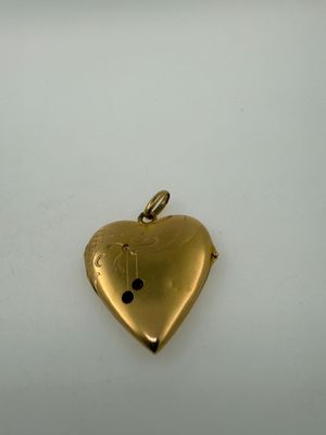 a close up of a gold heart pendant on a white surface