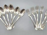 six silver plated forks and spoons on a gray surface