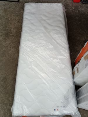 un matelas emballé dans du plastique, posé à même le sol