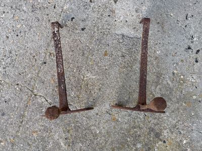 deux clous rouillés, placés l'un à côté de l'autre sur une surface en béton