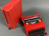 a small red typewriter next to a red case