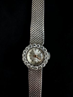 a close up of a watch on a black surface with a black background