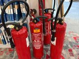 quatre extincteurs sont alignés sur un tapis