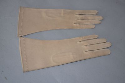 pair of beige leather gloves on a blue surface