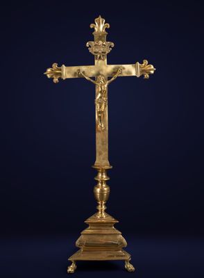 une croix en or posée sur un socle et surmontée d'une couronne