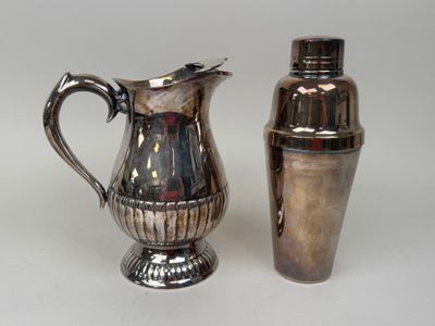 a silver pitcher next to a shaker on a table