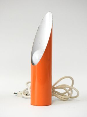 une lampe de table orange avec un pied blanc et un cordon qui y est fixé