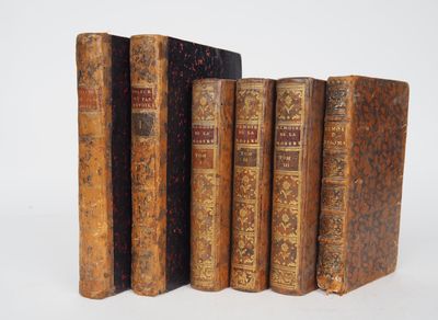 several old books are lined up in a row on a white surface