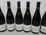 six bottles of wine are lined up on a table