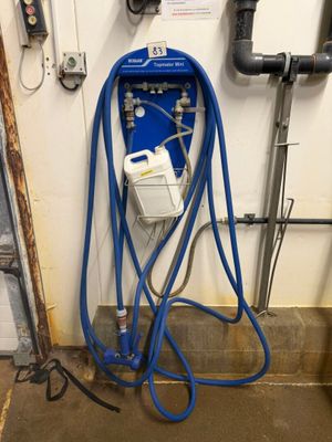 un tuyau bleu fixé au mur, à côté de tuyaux et de canalisations
