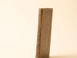 un vieux livre posé sur une table à côté d'un mur blanc
