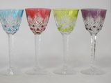 four different colored wine glasses sitting next to each other on a white surface