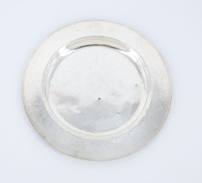 a silver plate on a white surface with a black dot