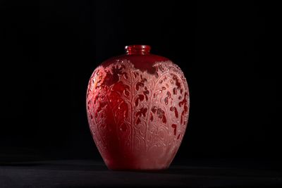 a red vase sitting on a table with a black background