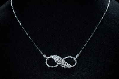 une femme portant un t-shirt noir et un collier en argent orné d'un nœud