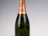 une bouteille de champagne posée sur une table blanche, sur fond gris