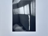 black and white photograph of a chair in a room with sunlight coming through the window