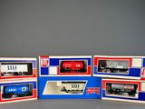 three boxed boxes of model train cars on a gray surface