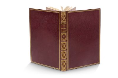un livre ouvert, aux tranches dorées et à la couverture rouge, posé sur une surface blanche
