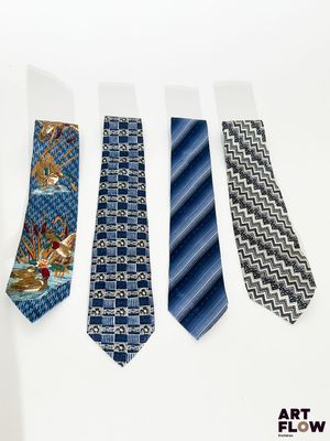 quatre cravates aux motifs variés sont alignées sur une surface blanche