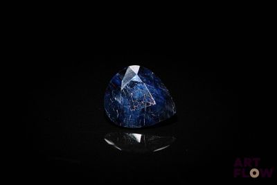 a close up of a blue sapphire stone on a black surface