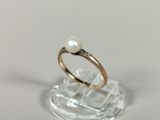 a ring with a pearl on top of a clear stand