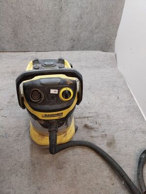 L'aspirateur jaune et noir est posé par terre, près du mur.