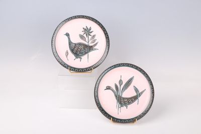 deux assiettes roses et noires ornées d'oiseaux, posées sur une surface blanche
