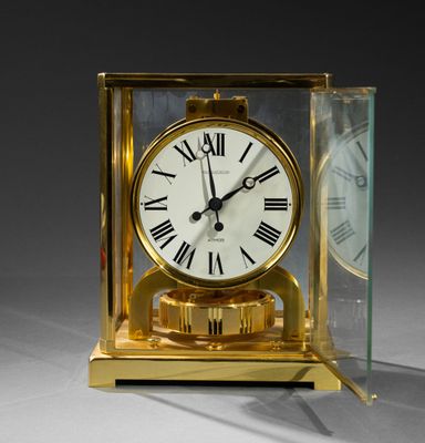 a gold clock with roman numerals and a glass case