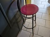 a red stool sitting in a kitchen next to a refrigerator