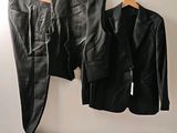 deux vestes en cuir noir accrochées au mur à côté d'un pantalon