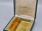 a box with six gold spoons in it
