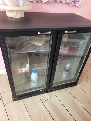 un petit réfrigérateur avec une porte en verre, sur lequel est posé un cupcake