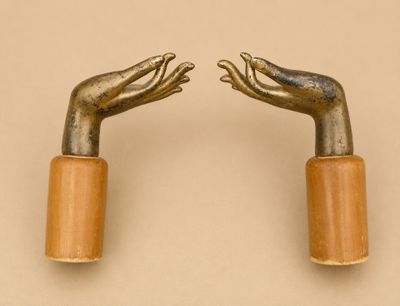 une paire de mains en métal avec des poignées en bois sur fond beige