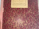 an old book with a red cover sitting on top of a table