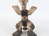 une image représentant une statue en bois d'un homme assis sur une surface blanche