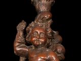 statue of a child holding a candle on a black background