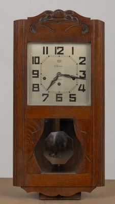 a wooden clock on a table with a white wall in the background