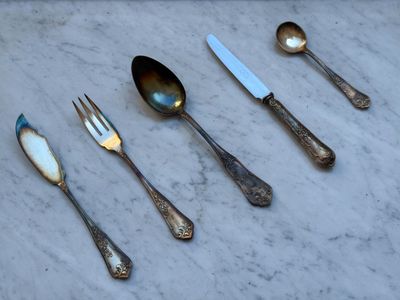 Plusieurs cuillères, fourchettes et couteaux sont alignés sur une table