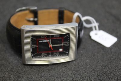 une montre posée sur une table, à laquelle est attachée une étiquette