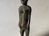une vieille statue en bois d'un homme avec un chapeau sur la tête