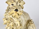 une statue représentant un chien assis sur une surface blanche