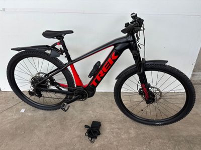 un vélo noir et rouge garé près d'un mur blanc