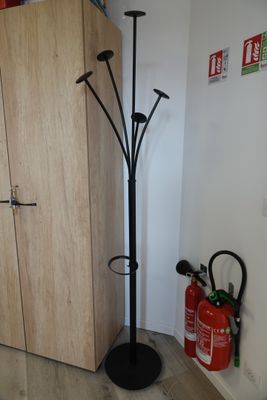 a coat rack and fire extinguisors in the corner of a room