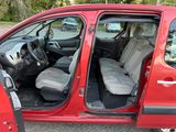 a small red car with its doors open in a parking lot