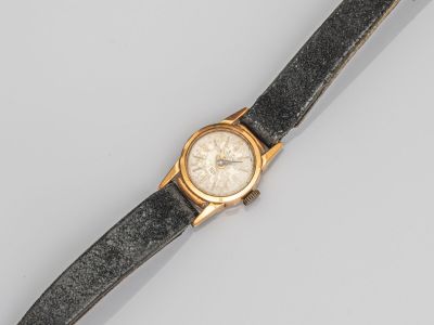 un gros plan d'une montre-bracelet posée sur une surface grise