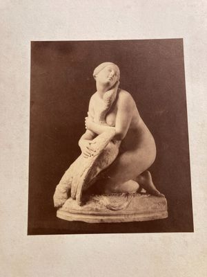 an old photo of a statue of a woman sitting on a rock