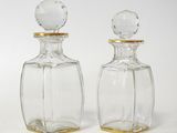 two clear glass bottles with gold rims on a white surface