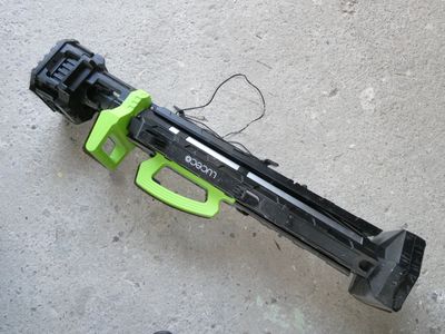 un pistolet jouet vert et noir posé par terre
